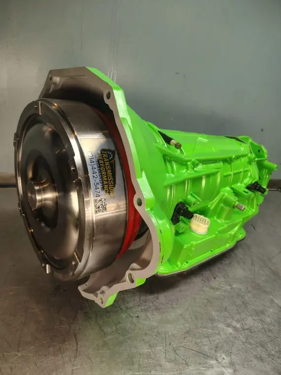 Transmisión reconstruida con acabado verde neón, con el convertidor de torque y la etiqueta del taller a la vista
